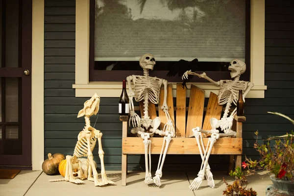 Eine Familie von Skeletten auf einem Wagen mit Wein und Hund. Gemütliche Idylle. Wohnkomfort im Herbst. Szenerie für Halloween im Oktober. Dekoration im Hof. — Stockfoto