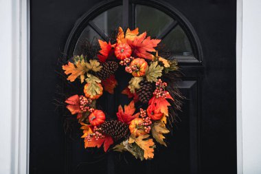 Ön kapıda yapraklarla, çiçeklerle ve balkabaklarıyla sonbahar çelengi. Ekim 'de Cadılar Bayramı için sahne. Bahçedeki dekorasyon..