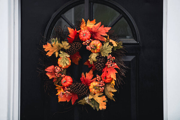 Осенний венок на входной двери с листьями, цветы тыквы. Пейзаж для Хэллоуина в октябре. Украшение во дворе.