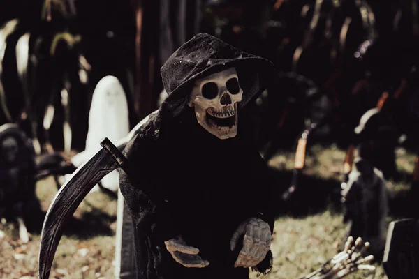 Morte nera con una falce nel cimitero. Scenario per Halloween in ottobre. Decorazione nel cortile. — Foto Stock