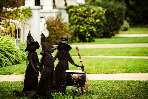 Τρεις μάγισσες ετοιμάζουν ένα μαγικό φίλτρο στο γκαζόν στην πίσω αυλή. Σκηνή για το Χάλογουιν τον Οκτώβριο. Διακόσμηση στην αυλή. — Φωτογραφία Αρχείου