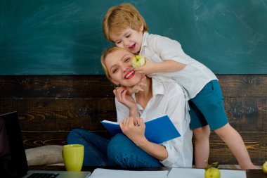 Favorite teacher. Boy preschooler hugs his teacher. Mother teaches her son at home school. Back to school