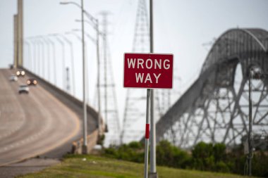 Bridge City, Texas, USA, - 2020: Wrong way road sign. The Rainbow Bridge crossing the Neches River in Southeast Texas. Dangerous road, the Scariest Bridge In US. Cool tourist destination