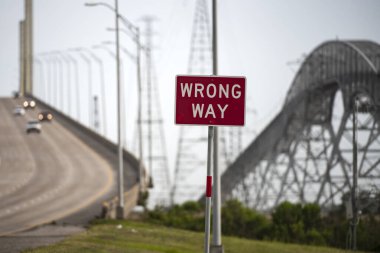 Bridge City, Texas, USA, - 2020: Wrong way road sign. The Rainbow Bridge crossing the Neches River in Southeast Texas. Dangerous road, the Scariest Bridge In US. Cool tourist destination