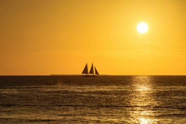Beautiful peaceful sailing at golden hour. Calm sea with a sailing boat silhouette at sunset