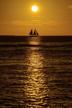Beautiful peaceful sailing at golden hour. Calm sea with a sailing boat silhouette at sunset