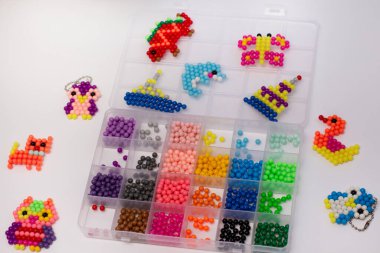 Handmade with children's hands, handmade aqua mosaic on the table, selective focus. Children's educational game aqua mosaic, inserts multicolored beads into the pattern with a special pen