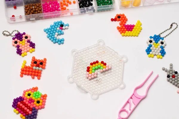 Handmade with childrens hands, handmade aqua mosaic on the table, selective focus. Childrens educational game aqua mosaic, inserts multicolored beads into the pattern with a special pen