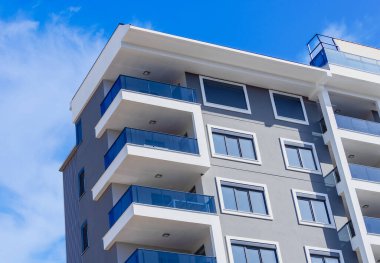 Mavi gökyüzünün arka planına karşı modern, yüksek katlı bir yerleşim yerinin köşesi..