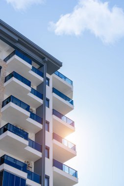 Güneşli bir günde, balkonları ve mavi gökyüzü olan bir apartmanın parçası..
