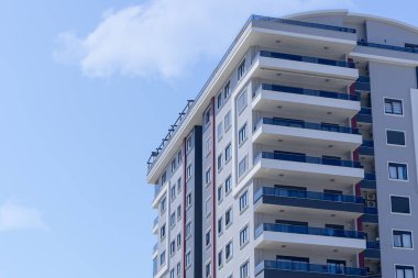 Balkonları ve bulutlu mavi gökyüzü olan bir apartmanın parçası..