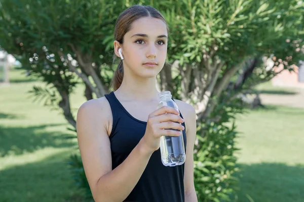 Nastoletnia Dziewczyna Słuchawkami Bezprzewodowymi Trzyma Butelkę Wody Pitnej Ręce — Zdjęcie stockowe