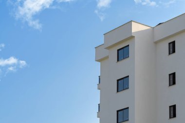 Exterior of a modern apartment building against a blue sky with clouds. Residential Properties.