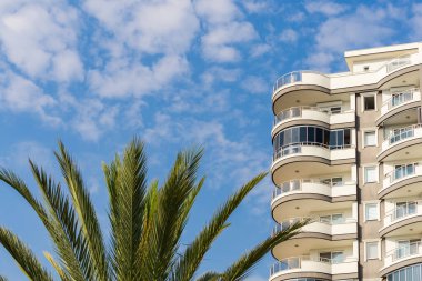 Exterior of a modern apartment building against a blue sky with clouds. Residential Properties.
