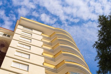 Exterior of a modern apartment building against a blue sky with clouds. Residential Properties.