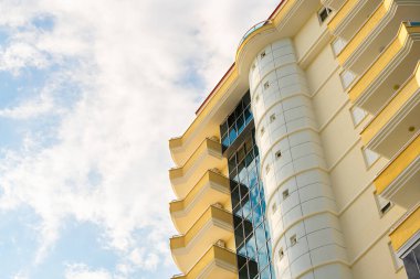 Exterior of a modern apartment building against a blue sky with clouds. Residential Properties.