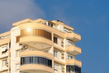 Exterior of a modern apartment building against a blue sky with clouds. Residential Properties.