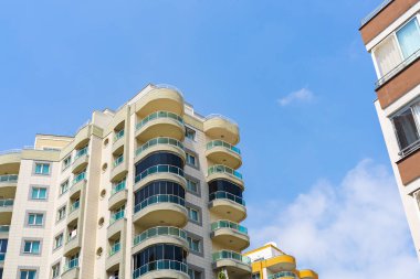Exterior of a modern apartment building against a blue sky with clouds. Residential Properties.