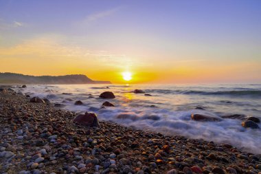 Seascape at sunset. Rocky coast. Long exposure, blurry water.