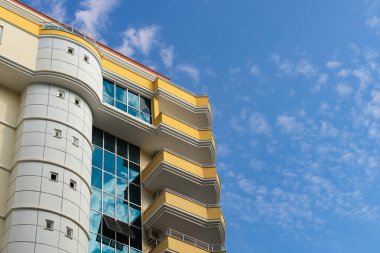 Exterior of a modern apartment building against a blue sky with clouds. Residential Properties.