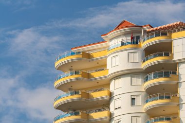Exterior of a modern apartment building against a blue sky with clouds. Residential Properties.