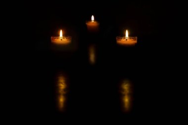 Karanlık arka planda yanan bir grup mum ışığı anma günü için ön planda bulanık ışık yansıması, anma konsepti.