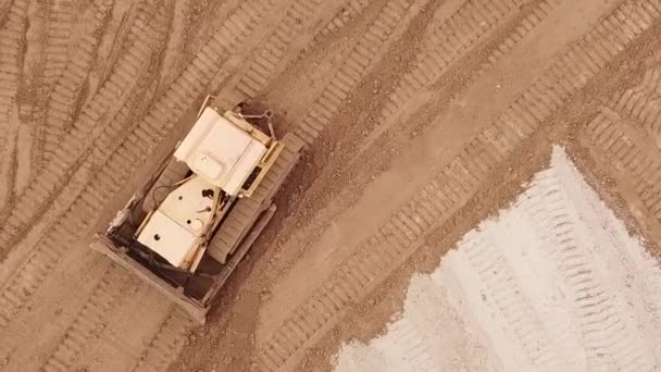 Gelber Bagger oder Planierraupe arbeitet auf Baustelle mit Sand, Luftaufnahme oder Draufsicht — Stockvideo