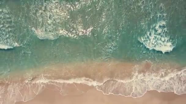 Aerial top view turquoise sea waves break on empty sand beach. Clean sea waves from birds eye view, ocean waves reaching shore and splashing from above — Vídeo de Stock