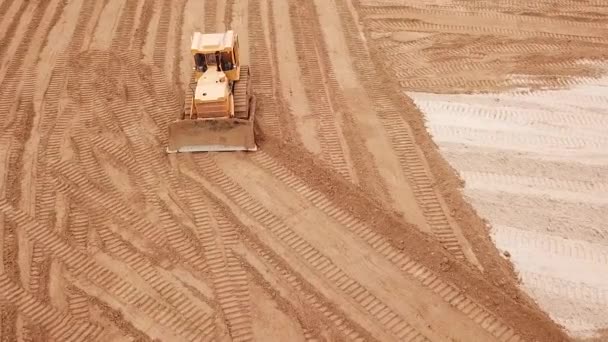 Escavadeira amarela ou bulldozer obras em canteiro de obras com areia, vista aérea ou superior — Vídeo de Stock