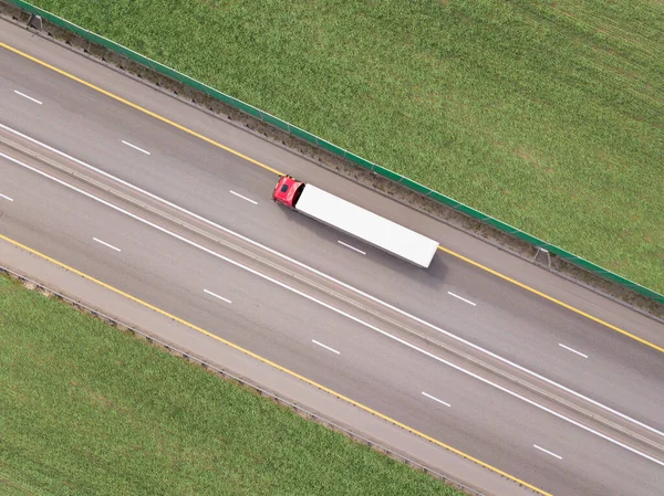 Dump trucks carrying goods on the highway. Red truck driving on asphalt road along the green fields. seen from the air. Aerial view landscape. drone photography. cargo delivery — Stock Photo, Image
