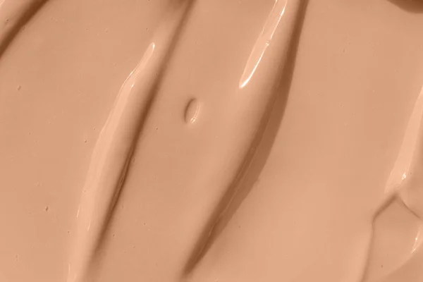 Beige nude liquid foundation smear, concealer texture smudge. Make up base drops, cream textured background. Closeup macro. Cosmetic tonal makeup moisturizer, bb cream swatch