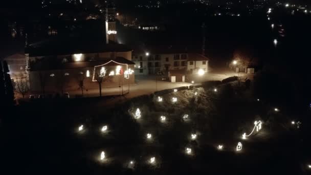 Orbit 4k drone night flying above medieval Italian catholic church decorated with illuminated Christmas figures — Stok video