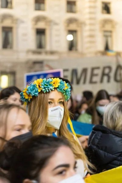 Mediolan, 24 lutego 2022. Kobieta w niebiesko-żółtym wieńcu jako znak protestu przeciwko rosyjskiej inwazji na Ukrainie. Spotkanie na Piazza Della Scala, Galeria Vittorio Emanuele II — Darmowe zdjęcie stockowe