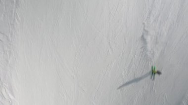 Kayak merkezinde snowboard yapan insanlar. Kayakçılar, snowboardcular karlı dağ yamacına çıkıyorlar. Açık hava kış sporu. Hava görüntüleri, üst görünüm, 4k video