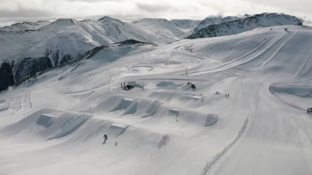 Livigno, Italy - February 21, 2022: People snowboarding and skiing at ski resort. Skiers and snowboarders riding snowy mountain slope. Outdoor winter sport. Aerial footage — Stock Video