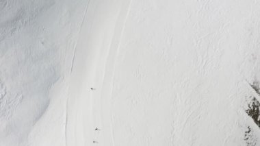 Livigno, İtalya - 21 Şubat 2022: Kayak merkezinde insanlar snowboard yapıyor. Kayakçılar, snowboardcular karlı dağ yamacına çıkıyorlar. Açık hava kış sporu. Hava görüntüleri, üst görünüm, 4k video