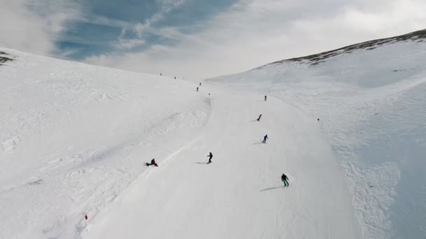 Livigno, Italy - February 21, 2022: People snowboarding skiing at ski resort. Skiers, snowboarders riding snowy mountain slope. Outdoor winter sport, scineric panoramic view. Aerial footage 4k — Stock Video