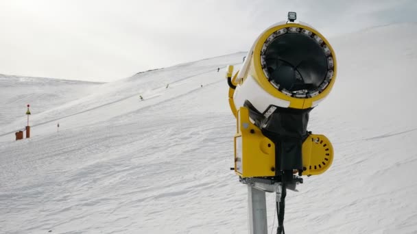 Sneeuwmachine, sneeuwkanon op skigebied Livigno, Italië op besneeuwde zonnige winterdag en skiërs skiën. Sneeuwkanon voor de productie van kunstsneeuw. 4k beeldmateriaal video — Stockvideo