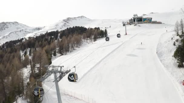 Livigno, Itália - 21 de fevereiro de 2022: vista aérea da estância de esqui de Livigno, na Lombardia, Itália. Cadeiras, elevadores de esqui, cabine de gôndola em movimento e esquiadores esquiando sobre o panorama da paisagem. Imagens de vídeo 4k — Vídeo de Stock