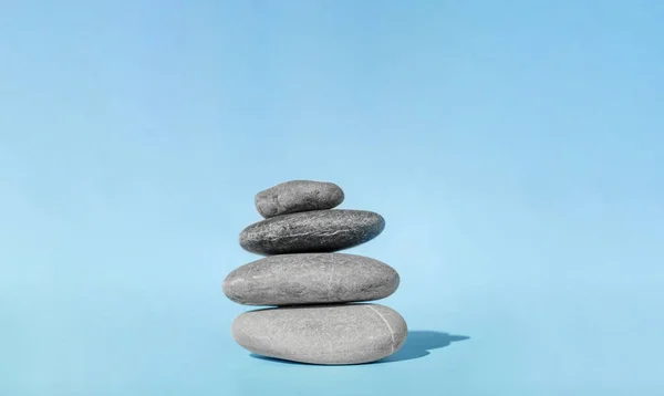 Balanserade sten för spabehandlingar på blå bakgrund. Balansröse - symbol för harmoni, lugn och avkoppling, begreppet meditation. — Stockfoto