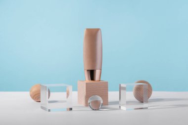 Cosmetic liquid foundation nude cream tube mockup on acrylic and wooden block podium pedestal. Beige concealer base cosmetics product mock up on blue backdrop. Skincare beauty primer, cc corrector clipart