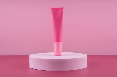 Podyum kaidesinde pembe kozmetik ürünü. Pembe arka planda yüz kremi modeli, kadın derisi için losyon. Güzellik nemlendirici ambalaj. Losyon sunumu