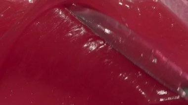 Kırmızı soyut balmumu kremi kozmetik arka plan videosu. Diş macunu dokusu spatula görüntüleriyle yayılıyor. Pembe yapışkan merhem, çocuklar için tatlı diş macunu.
