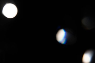 Mavi ışık prizması gökkuşağı parlamaları siyah arka plan, ışık geçişi kristalleri, prizmatik güneş yakalayıcı ışınları üzerinde etkiye sahiptir. Soyut bulanık renkli lensler koyu renk üzerinde parlıyor.