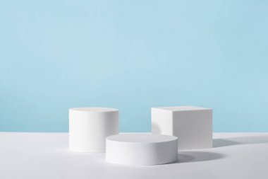 Mavi arka planda kozmetik ürün ambalajı için podyum kaidesi. Mücevher sunumu için vitrin, parfüm reklamı için beyaz platform, kozmetik standı, markalaşma sahnesi