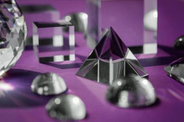 Işığı kıran kristal prizma, sihirli kristaller ve piramit, mor arkaplanda küre ve küp. Ruhsal şifa kristal pratiği. Feng Shui, iyi enerji akışı konsepti..