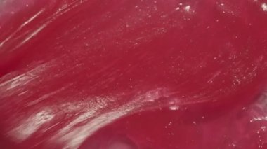 Balmumu kremi kozmetik arka plan videosu. Pembe yapışkan merhem, çocuklar için tatlı diş macunu, jöle. Kırmızı diş macunu deseni spatula ile yayılıyor. 