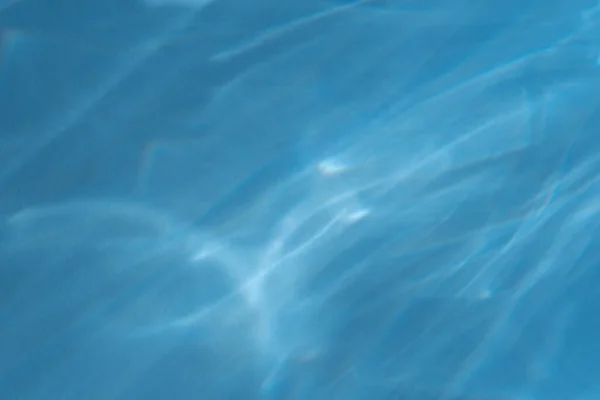Каустичний ефект світлового заломлення на синій стіні накладає фото макет, розмиті сонячні промені заломлюються через скляну призму з тіні. Абстрактний силует заломлення природного світла на поверхні води — стокове фото