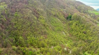 Lombardy, Kuzey İtalya 'daki küçük Pasturo kasabasının klibinde dağ manzarası, orman ve küçük köydeki eski kulübeler görülüyor. Çekim 4k