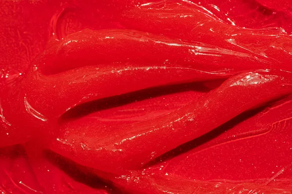 Kırmızı jel dokusu. Kozmetik temiz sıvı krem lekesi. Cilt bakım ürünleri numunesi yakın çekim. Diş macunu ya da balmumu